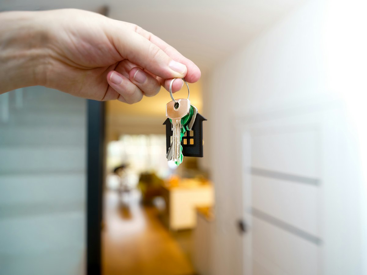 A hand holding a new set of house keys at the front door